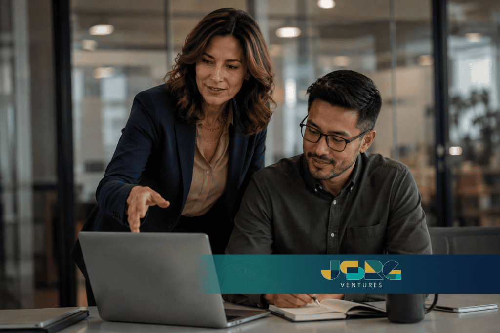 A fractional CMO reviewing strategy on a laptop with a colleague, illustrating hands-on guidance for a smaller company weighing the role.