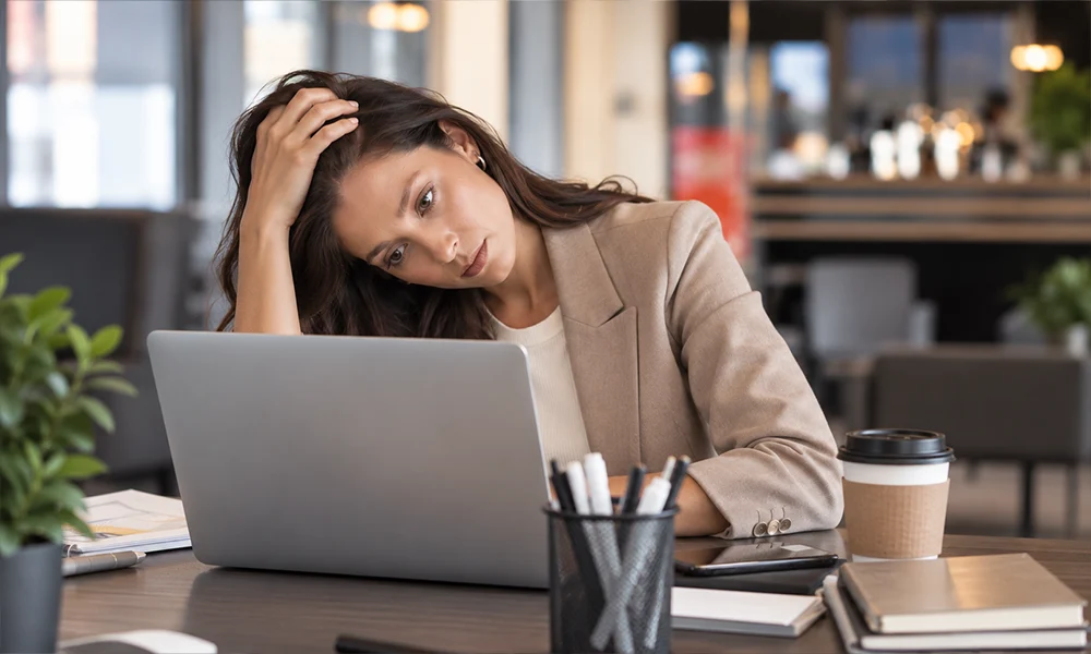 Stressed marketer staring at her laptop, needing SEO, AEO, and GEO strategy to get her business found online